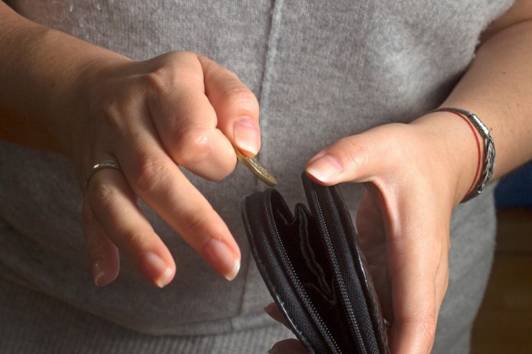 person putting coin inside wallet