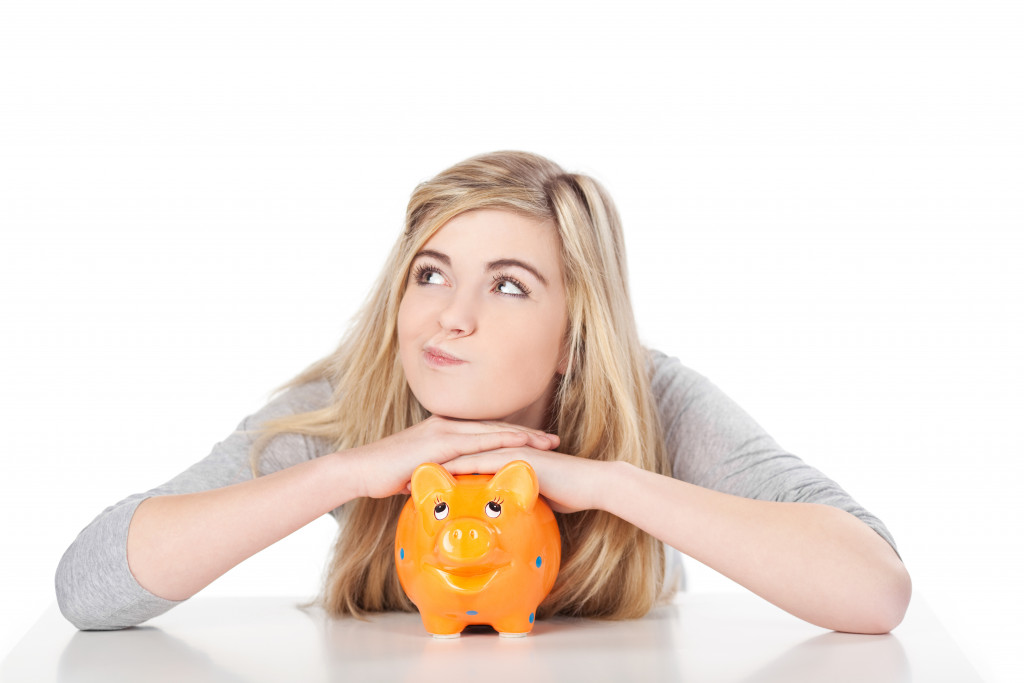girl resting her head on top of an orange piggy bank