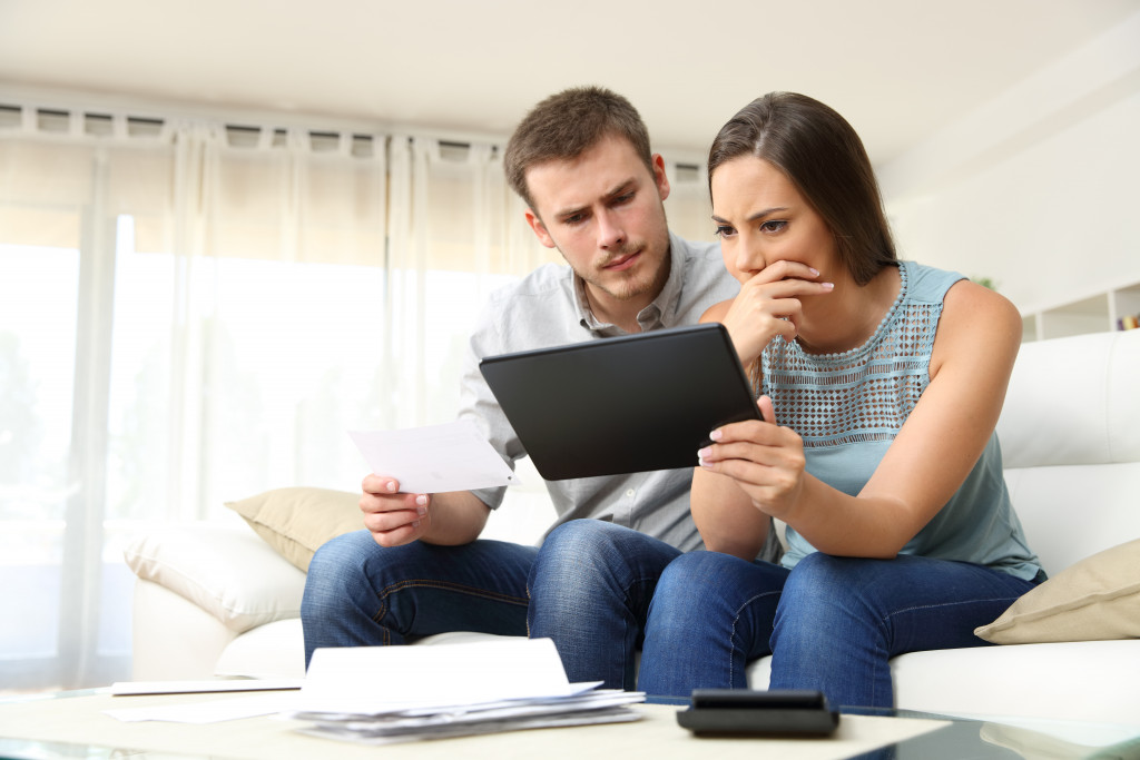 couple sitting in a couch looking at their bills