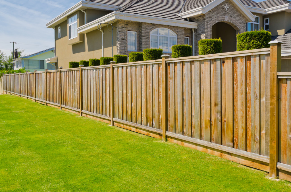 A big house lot with a whole stretch of wooden fence